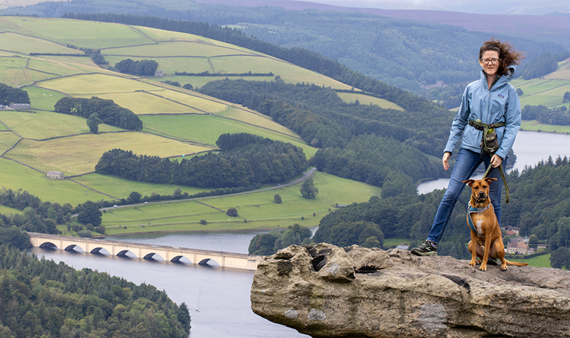 Sierra and our dog Finn standing on a rock formation with ladybower reservoir in the background